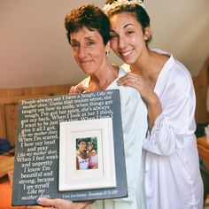 two women holding up a framed photo with the words, people always say i love you