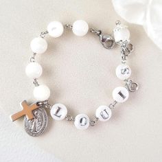 This stunning Baptism bracelet is a truly divine piece that combines elegance and spiritual significance. Crafted with natural mother of pearl beads, it features gold plated virgin Mary and cross charms that symbolize protection and faith. The bracelet is personalized with a handcrafted initial letter, adding a unique touch to this meaningful piece. Perfect for commemorating a special occasion or as a thoughtful gift, this bracelet is a beautiful reminder of faith and blessings. *MATCHING ROSARY PRAYER: https://www.etsy.com/au/listing/1492666531/personalized-rosary-beads-pearl-rosary *Materials:  High Quality 18k gold plated Stainless Steel charms * Gemstone: Genuine mother of pearl beads, round shape, 6mm * Closure: adjustable finial, lobster clasp * Letter beads: handmade, mother of pear White Name Bracelets For Wedding, Personalized White Bracelets For Wedding, White Hypoallergenic Pearl Bracelet For First Communion, Hypoallergenic White Pearl Bracelet For First Communion, Adjustable White Name Bracelet Nickel Free, Adjustable Nickel-free White Name Bracelet, White Engraved Bracelets For Personalized Gift, Adjustable White Nickel-free Name Bracelet, Personalized White Engraved Bracelets