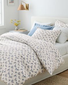 a bed with white sheets and blue flowers on it