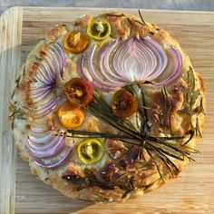 a pizza with onions, tomatoes and herbs on it