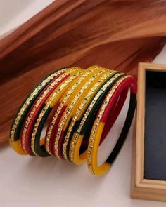 a stack of bangles sitting on top of a table next to a wooden frame