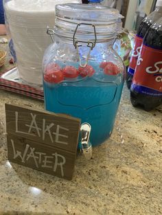 there is a lake water sign next to a mason jar with red balls in it