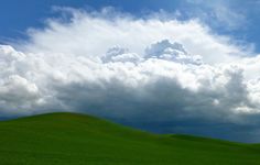 a green field with clouds in the sky