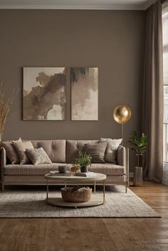 a living room with two paintings on the wall and a coffee table in front of it