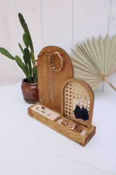 a wooden box with jewelry in it sitting next to a cactus