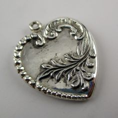 "This antiqued sterling silver, two-sided Acanthus Heart charm features a complex design of Victorian beads, musical clefs, and showy foliage. Made by Brown County Silver. Vintage and in new, never worn condition. Approximately 30 years old. 1 1/8\" high 1\" wide 3.7 grams *Notice this heart does not include a jump ring See more @ https://www.etsy.com/shop/brocosi" Silver Heart Necklace With Heart Beads, Silver Heart Bead Pendant Necklace, Silver Heart Pendant Necklace With Heart Beads, Silver Double Heart Necklace With Heart Beads, Nickel-free Silver Heart Necklace For Memorials, Nickel-free Silver Heart Necklace For Memorial, Silver Nickel-free Heart Necklace For Memorial, Silver Heart-shaped Etched Jewelry, Etched Heart Silver Jewelry