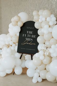 the future mrs sign is surrounded by white balloons and an arch with flowers on it