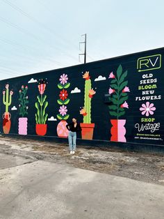 a person standing in front of a wall with flowers and plants painted all over it