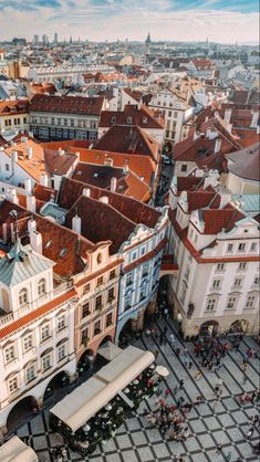 an aerial view of the city with many buildings and people walking around it on a sunny day