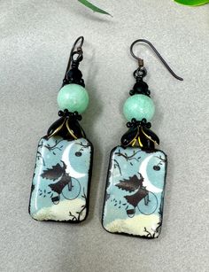 Ceramic charms from an Etsy artisan are topped with enameled black bead caps, sprocket spacers, green Angelite Jade and topped with jet black glass beads. Niobium ear wires. Bohemian Metal Earrings For Halloween, Whimsical Green Hand Painted Earrings, Bohemian Green Dangle Beads, Green Halloween Dangle Earrings, Green Hand-painted Bohemian Earrings, Beaded Boho Jewelry, Artisan Earrings, Paper Jewelry, Halloween Earrings