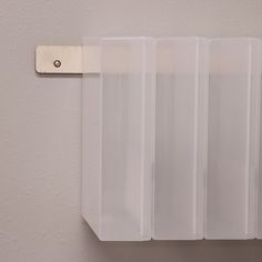 three clear plastic bags hanging from a hook on a white wall with a wooden tag attached to it