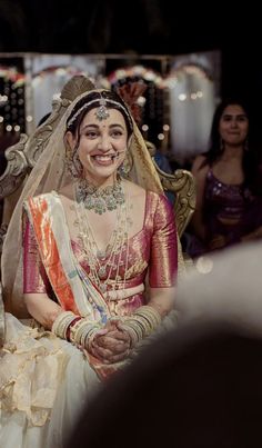 a woman in a bridal dress sitting on a chair with other people around her