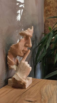 a wooden table topped with a statue of a man's head on top of a piece of wood