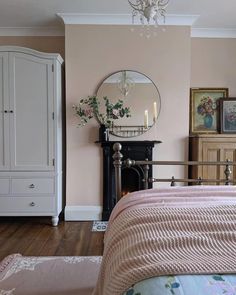 a bedroom with a bed, dresser and mirror on the wall next to a fireplace