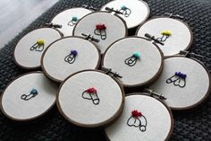 several embroidery hoops with scissors on them sitting on top of a black cloth covered table