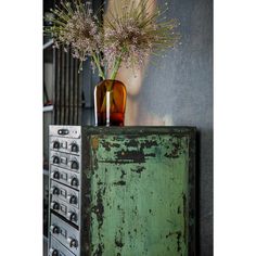 a vase with flowers sitting on top of an old cabinet