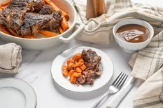 a table topped with meat and vegetables next to a bowl of sauce on top of a white plate