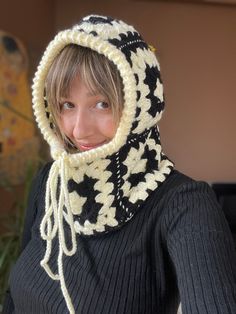 a woman wearing a black and white knitted hat with a hood on her head