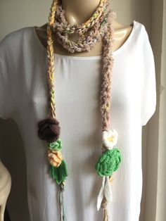 a woman wearing a crocheted necklace with tassels and beads on it