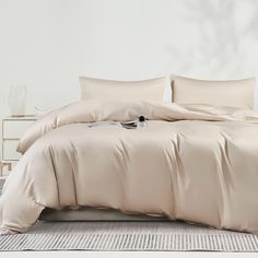 a bed with beige sheets and pillows on top of it in a room next to a white wall