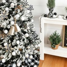 a decorated christmas tree with black and white ornaments on it next to a wooden shelf