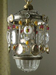 a chandelier hanging from the ceiling with lots of beads and charms on it