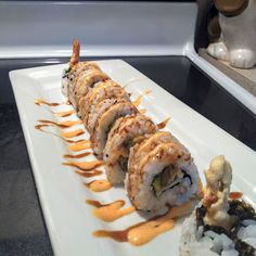 sushi rolls on a white plate with sauce drizzled over the top