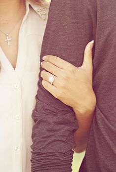 a close up of a person wearing a ring on their finger and holding another persons arm