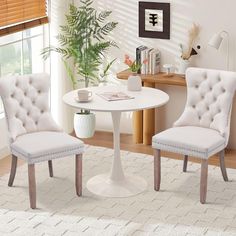 a white table with two chairs and a vase on the floor in front of it