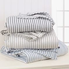 three folded sheets sitting on top of a white table next to a pair of windows