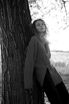 black and white photograph of woman leaning against tree