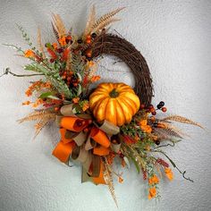 a fall wreath with pumpkins and greenery