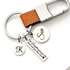 a couple of key chains that are on top of a white table with a brown leather strap