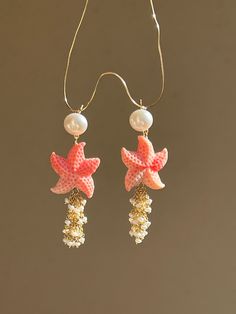 Joyful summer earrings, ideal for a beach vacation! Two starfish are made of carved conch shell, adorned with cascade of tiny fresh water pearls. The pearl studs are 18k gold filled.  MATERIAL Conch shell, freshwater pearls, gold filled   SPECIFICATIONS Length 6 cm Handmade in Spain Earrings come in a gift box Worldwide shipment with registered, trackable post Care for gold filled jewelry: avoid contact with humidity, swimming pool water and chemicals. Clean with soft dry polishing cloth.  Care Summer Starfish Charm Dangle Earrings, Summer Dangle Earrings With Starfish Charm, Summer Shell Starfish Jewelry, Dangle Earrings For The Beach, Summer Starfish Shell Jewelry, Pierced Dangle Earrings For Beach, Summer Starfish Charm Drop Earrings, Ocean-inspired Shell With Starfish Charm For Summer, Summer Ocean-inspired Shell With Starfish Charm