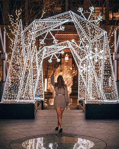 a woman is walking through an archway decorated with christmas lights