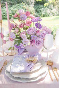 the table is set with pink and purple flowers