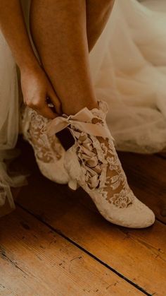 a bride tying her wedding shoes on the floor