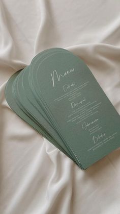 four green menu cards sitting on top of a white sheet