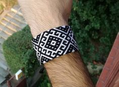 a man is wearing a black and white bracelet on his wrist with an intricate pattern