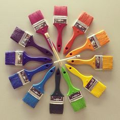 nine paint brushes arranged in a circle on top of each other, with different colors