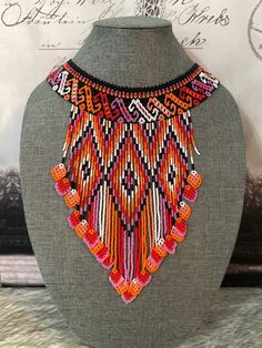 an orange and black beaded necklace on a mannequin neck piece with writing in the background