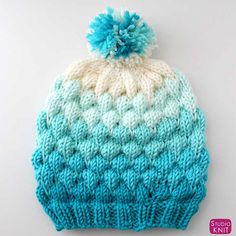 a blue and white knitted hat with a pom - pom on top