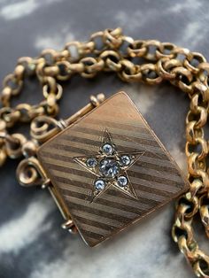 "A crisp and sharp late Victorian square, diagonally set locket. It is gold filled, testing at 14k, and features a central paste starburst set into wonderful geometric pin stripping to the front. The bale and mounting are ornate and well wrought.  The square shape, as well as the style of bale, both indicate that this piece was originally worn on a watch chain as a fob. It opens easily with the help of a small notch on one side, and clicks shut securely. Once open, the plain interior reveals the paste stones to be set open backed; punched through the metal of the locket's front half. The inter of its back half other side reads \"W & H Co\" inside of a heart indicating its manufacturer:a Wightman & Hough, jewelers from Providence, Rhode Island. Active between 1856-1922, they became well reg Antique Engraved Square Pendant Jewelry, Rectangular Vintage Charm Jewelry For Formal Occasions, Vintage Star-shaped Wedding Jewelry, Antique Square Locket Pendant Jewelry, Antique Square Pendant Locket Jewelry, Vintage Square Pendant Jewelry Engraved, Vintage Engraved Square Pendant Jewelry, Victorian Rectangular Locket Jewelry, Victorian Style Rectangular Locket Jewelry