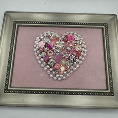 a heart made out of buttons in a silver frame on a pink background with beading