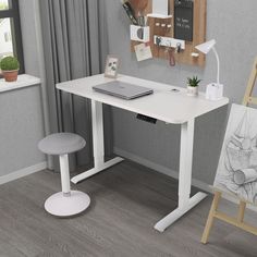 a white desk with a laptop on it next to an easel and other items