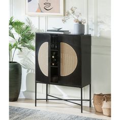 a black cabinet with wicker doors and an oval design on the door, next to a potted plant