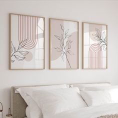 three paintings hang above a bed with white sheets and pillows on the headboard in a bedroom