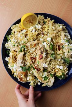 a blue plate topped with rice and chicken next to a lemon wedge on top of a wooden table