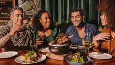 three people sitting at a table with plates of food and drinks in front of them