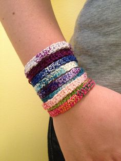 a woman wearing a bracelet made with multicolored crocheted yarns on her arm